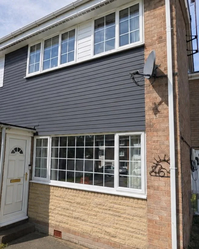 Same house frontage after repainting, with dark grey timber cladding