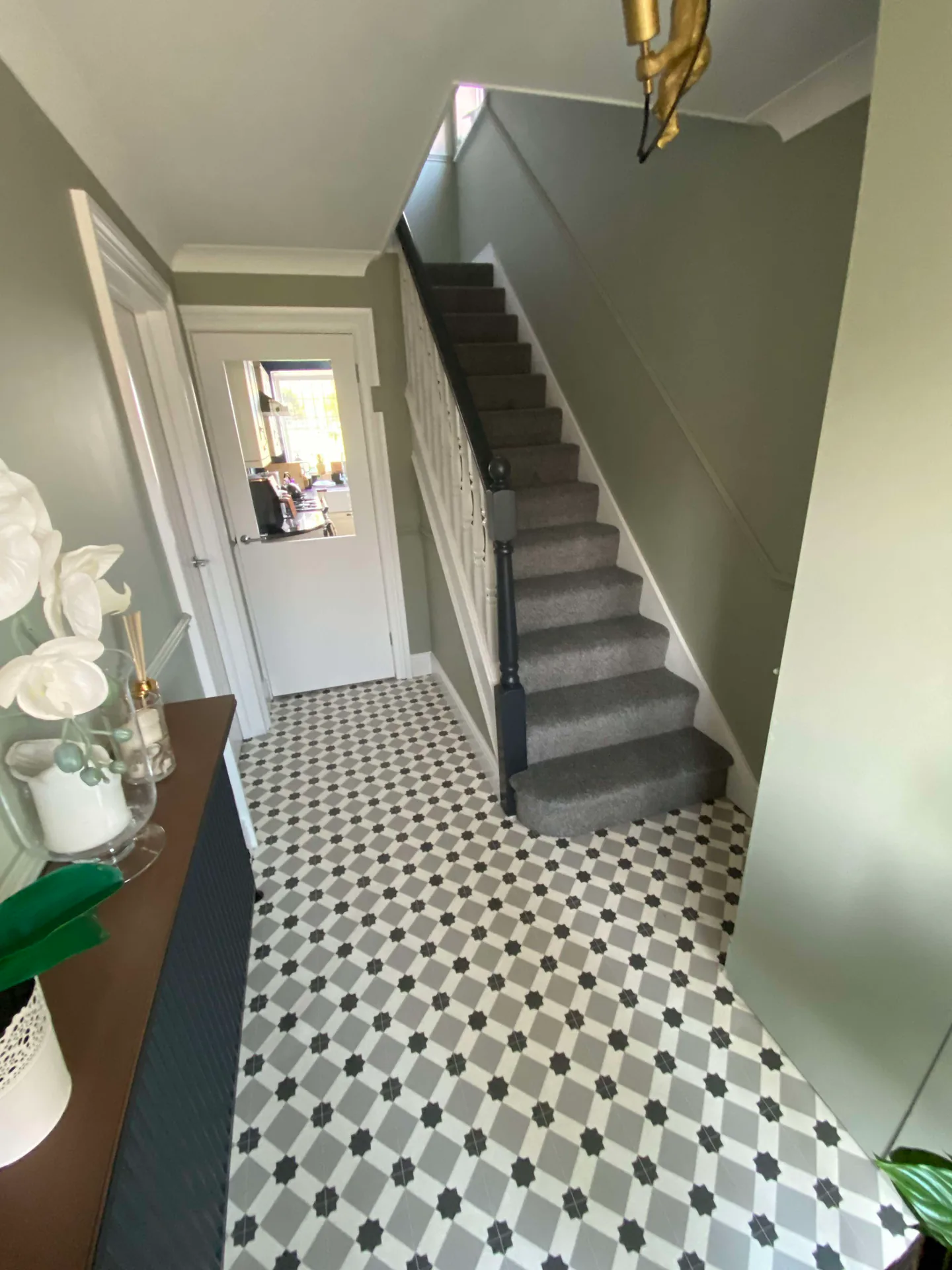 Freshly decorated entrance hall with grey-green walls and patterned tile floor