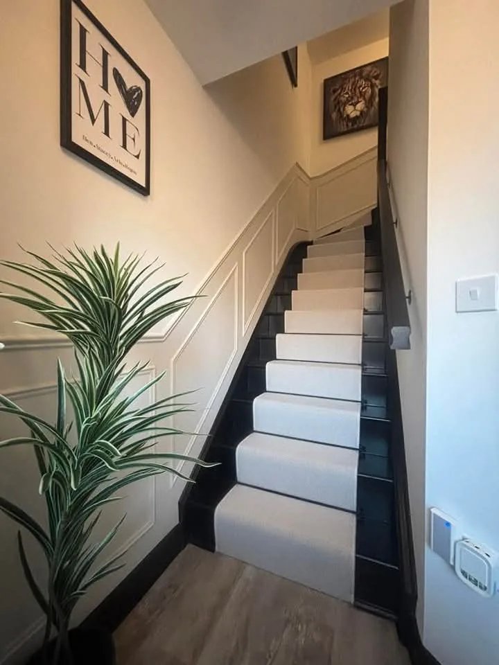 Finished staircase with pale walls, white risers, dark trim and a fitted handrail