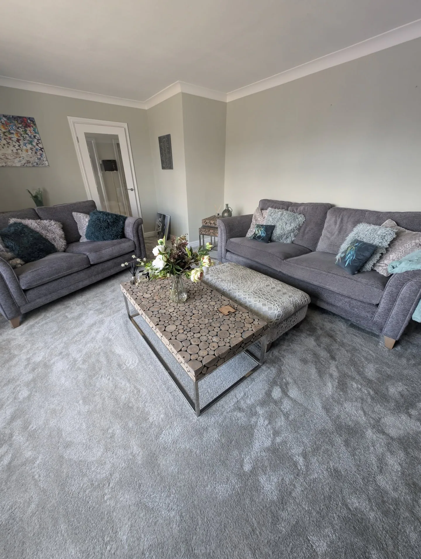 Grey lounge with crisp white coving, coordinated sofas and pale carpet