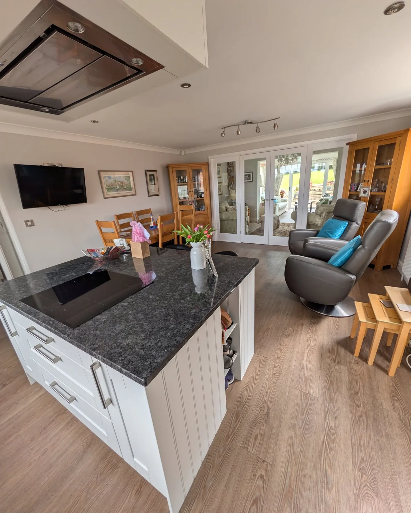 Bright open-plan kitchen and living area with white cabinetry and pale walls