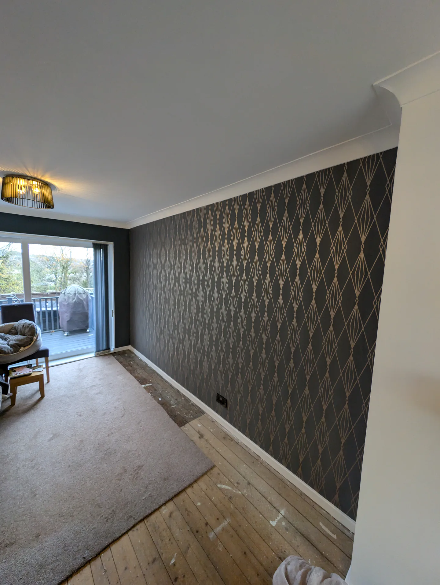 Lounge with a dark geometric wallpaper feature wall and freshly painted trim